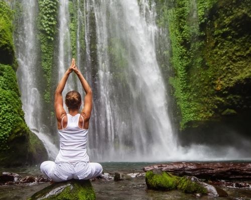 Woman Practicing Yoga By Waterfall
