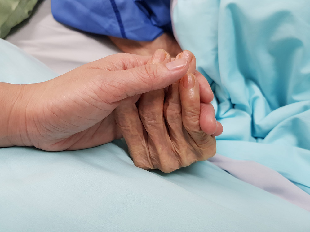 holding hands of a dying elderly person